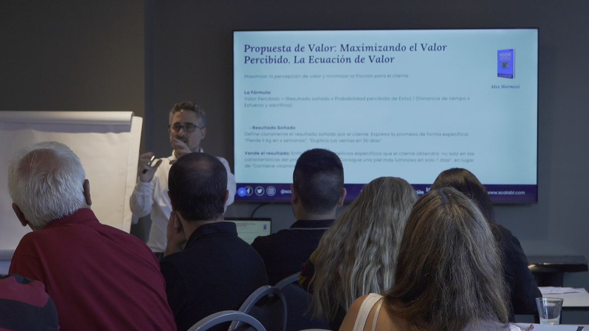 Sala con participantes de espaldas mirando la pantalla mientras Francisco Santolo explica junto a un rotafolio.